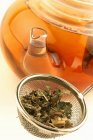 Крупный план сухих чайных листьев в решето и чайнике — стоковое фото