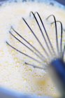 Closeup view of whisk in cream with air bubbles — Stock Photo