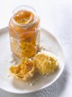 Orange marmelade in jar over white plate — Stock Photo