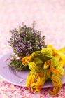 Размещение цветущего тимьяна и желтой кургеты с цветами на тарелке — стоковое фото