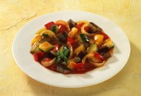 Ratatouille on white plate over yellow surface — Stock Photo