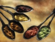 Selection of mustards in spoons over wooden surface — Stock Photo