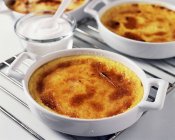 Closeup view of Creme Brulee in baking dishes and cream — Stock Photo