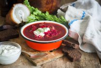 Traditionelle russische und ukrainische Rote-Bete-Suppe namens Borscht in roter Schüssel über Holztisch mit Löffel — Stockfoto