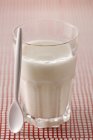 Склянка молока з ложкою — стокове фото