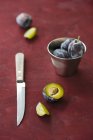 Damsons with metal cup and knife — Stock Photo