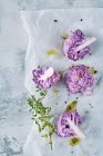 Purple cauliflower with thyme and olive oil on baking paper — Stock Photo