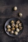 Ovos de codorna em tigela de metal e na superfície rústica — Fotografia de Stock