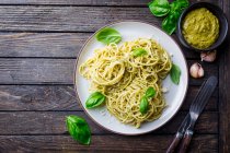 Spaghetti pasta with homemade pesto sauce on wooden background — Stock Photo