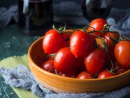 Rohe Tomaten in einer rustikalen Schüssel auf dunklem Hintergrund — Stockfoto