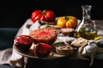 Tomates ecológicos rojos y amarillos con aceite de oliva, ajo, sal y pan para ensalada o bruschetta - foto de stock