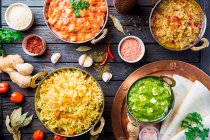 Different bowls with assorted indian food: chicken, curry rice, lentils, paneer, chapati and spices — Stock Photo