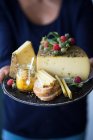Una donna con un vassoio di formaggio alle erbe selvatiche, pane e chutney — Foto stock