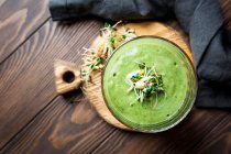 Green vegan smoothie with spinach, banana and sprouted seeds on dark wooden background — Stock Photo