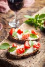 Crostini appetizers with cherry tomatoes, basil, and cheese — Stock Photo