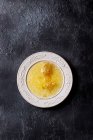 Honeycoms en miel líquida en placa vintage blanca sobre fondo de textura negra - foto de stock