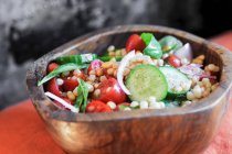 Israeli couscous salad with cucumbers, tomatoes and fresh basil in wooden bowl — Stock Photo