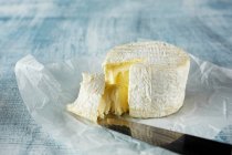 Мягкий сыр с ножом для сыра на бумажной упаковке — стоковое фото