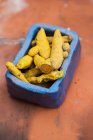 Dried turmeric roots in a blue ceramic bowl — Stock Photo