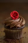 Um cupcake de chocolate com uma cobertura de creme e uma rosa de maçapão — Fotografia de Stock