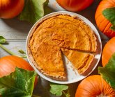 Homemade pumpkin pie with autumn leaves on a wooden background. top view. — Stock Photo
