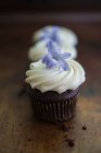Mini cupcakes de chocolate com cobertura de creme e flores roxas — Fotografia de Stock