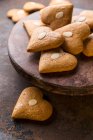 Cuori di pan di zenzero con mandorle scaglie su piatto di legno — Foto stock