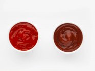 Two bowls of ketchup against a white background (top view) — Stock Photo