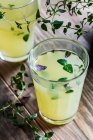 Lemonade with thyme in glasses on wooden surface — Stock Photo