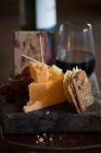 Cheese board still life with cheddar, crackers and wine — Fotografia de Stock
