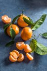 Mandarini interi e sbucciati su superficie di pietra — Foto stock