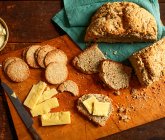 Pão de refrigerante e biscoitos com manteiga e queijo em tábua de corte de madeira — Fotografia de Stock