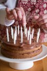 Um bolo de aniversário sendo decorado com velas — Fotografia de Stock