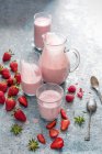 Fresas y frambuesas bebiendo yogur en vasos y jarra - foto de stock
