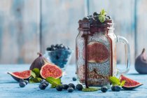 Glass jar of healthy breakfast with muesli, pudding with chia seeds, fresh fig and berries — Stock Photo