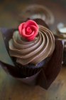 Um cupcake de chocolate com uma cobertura de creme e uma rosa de maçapão — Fotografia de Stock