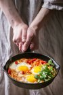 Traditional Israeli Cuisine dishes Shakshuka (Fried egg with vegetables tomatoes and paprika in cast-iron pan in female hands) — Stock Photo