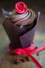 Una magdalena de chocolate con cobertura de crema y rosa de mazapán - foto de stock