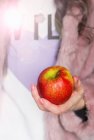 Червоне і зелене яблуко тримають у жіночій руці — стокове фото