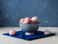 Pink and white meringues in blue bowl and on cloth napkin — Stock Photo