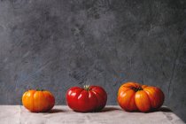 Three red and yellow tomatoes on table — Stock Photo