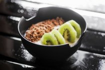 Joghurt mit Müsli und Kiwi in einer schwarzen Schüssel — Stockfoto