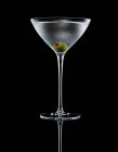Martini com azeitona recheada em vidro sobre fundo escuro — Fotografia de Stock