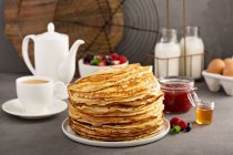 Big stack of homemade crepes or thin pancakes with butter, jam and honey — Stock Photo