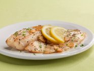 Tilapia fillets with garlic and lemon slices — Stock Photo