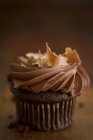 Un cupcake au chocolat avec une garniture crème et des copeaux de chocolat — Photo de stock
