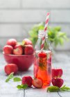 Erfrischendes Sommergetränk mit Erdbeere in Glasflasche auf weißem Holztisch — Stockfoto