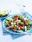 Salada grega com salsichas servidas em prato com talheres — Fotografia de Stock