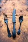 Coltello vintage nero forchetta e cucchiaio su un'ardesia di rame — Foto stock