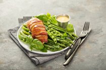 Bacon wrapped chicken breast with asparagus and spring peas — Stock Photo
